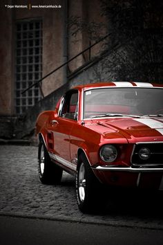 an old red car is parked on the street