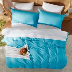 a bed with blue and white comforters on top of it next to a potted plant