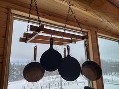 pots and pans hanging from the ceiling in front of a window with snow outside