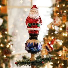 a santa clause ornament sitting on top of a christmas tree