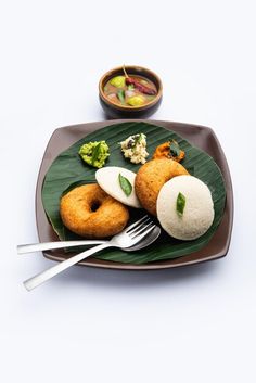 a plate with some food on it next to a bowl of soup and a fork