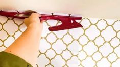 a person is using a pair of scissors to cut the trim on a tile wall