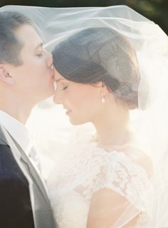 a bride and groom kissing under a veil