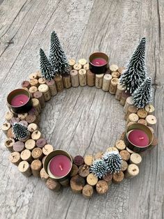 a wreath made out of wine corks with candles and pine cones on top, sitting on a wooden table