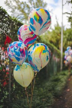 some balloons that are in the air with paint splattered on them and one balloon has been tied to it