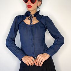 Elevate your wardrobe with this vintage navy blue blouse, featuring a charming keyhole neck and Y2K-inspired ruffle collar. Crafted from a comfortable cotton blend, this long-sleeved top exudes sophistication and style. With a buttoned sweetheart neckline, it adds a touch of elegance to any outfit.  Designed by Josep Font* and made in Spain, this secretary blouse is a timeless addition to your collection. *Josep Font is one of the most important fashion designers in Spain, awarded really young and with an amazing savoir-faire. His homonymous brand disappeared in 2011 and then he started to work and completely change and renew DelPozo's fashion house! * Size: Tagged as 36 size, but feels a bit larger! But, please, check measurements below! Thank you! :) * Condition: Very good vintage condit Blue Fitted Top With Ruffled Collar, Blue Cotton Tops With Ruffled Collar, Blue Ruffled Collar Blouse For Fall, Navy Collared Blouse For Summer, Casual Blue Top With Ruffled Collar, Casual Blue Tops With Ruffled Collar, Blue Cotton Blouse With Ruffled Collar, Blue Collared Ruffle Top, Vintage Blue Ruffled Blouse