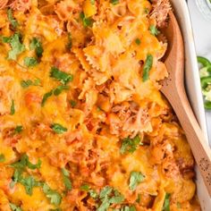 a casserole dish with meat, cheese and parsley in it on a wooden spoon