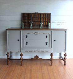 an old dresser is painted white and has two glass vases on top of it