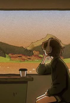 a person sitting at a table with headphones on, looking out the window and mountains in the background