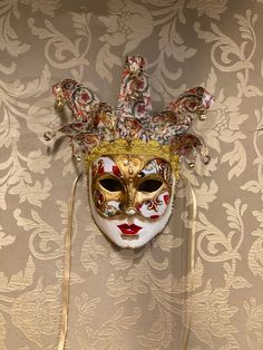 a mask hanging on the wall in front of a damask background