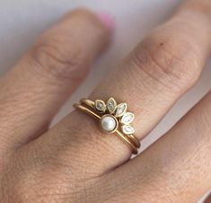 a close up of a person's hand wearing a gold ring with pearls on it