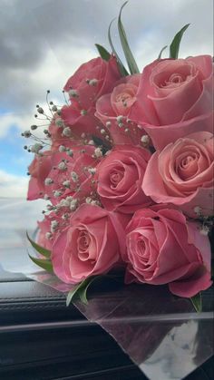 a bouquet of pink roses sitting on top of a car