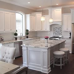 a large kitchen with white cabinets and marble counter tops, along with an island in the middle