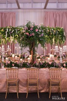 the table is set with pink and white flowers, greenery, candles and chandeliers