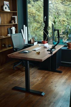 a wooden desk sitting in front of a window next to a book shelf filled with books