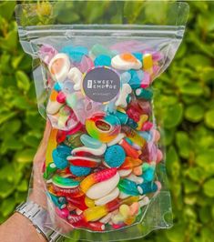 a bag filled with lots of colorful candies in front of some bushes and trees