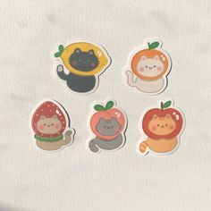 four stickers with different animals and fruits on the top one has a cat, an apple, and two are oranges