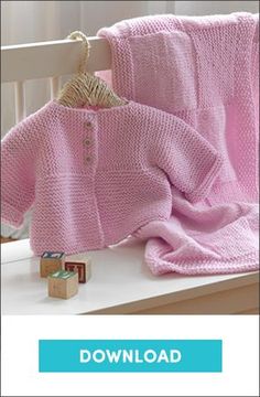 a baby's pink knitted sweater and blanket sitting on top of a white crib