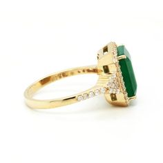 a gold ring with an emerald and diamonds on the side, set in 18k yellow gold