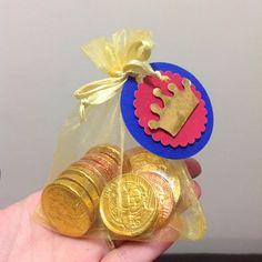 a hand holding some gold coins and a blue tag with a red heart on it