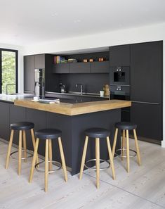 a kitchen with black cabinets and stools next to an island in front of a window