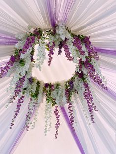 the purple and white flowers are hanging from the ceiling