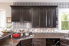 a kitchen with dark wood cabinets and checkered wall paper on the backsplash