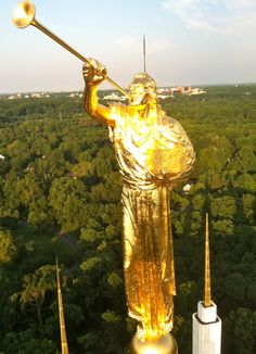 a golden statue holding a trombone in front of trees