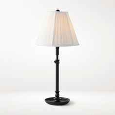 a black lamp with a white shade on it's base and a light bulb in the middle