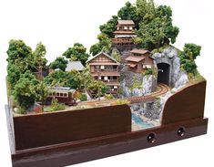 a model of a town with trees and houses on it's sides, in the middle of a wooden frame