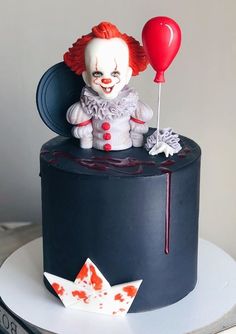 there is a cake with a clown on it and a balloon attached to the top