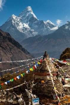 there is a mountain in the background with many flags on it and people walking around