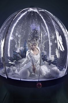 a glass ball with an image of a woman in white on it and snowflakes all around