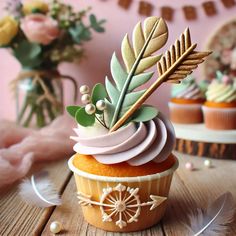 a cupcake with frosting and leaves on top sitting on a table next to other cupcakes