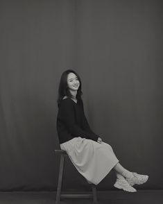 a black and white photo of a woman sitting on a chair with her legs crossed