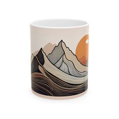 a coffee mug with mountains and sunsets on the side, in front of a white background