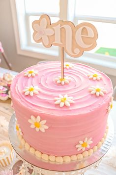 a pink cake sitting on top of a table