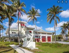 a white building surrounded by palm trees on a sunny day