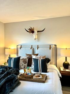 a bed with pillows, blankets and other items on it in a room that has white walls