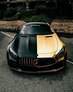 a gold and black mercedes sports car parked in a parking lot next to some bushes