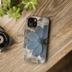 an iphone case sitting on top of a wooden table next to a camera and plant