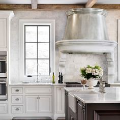 a kitchen with white cabinets and an island in front of a stove top oven next to a window