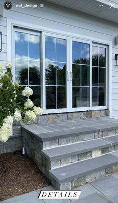 the steps leading to the front door are made out of stone and have white hydrangeas