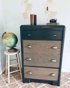 a black dresser with drawers and a globe on top