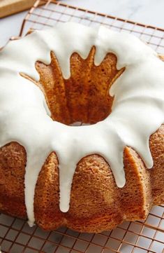 a bundt cake with white icing sitting on a cooling rack next to a knife