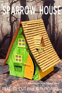 a paper doll house sitting on top of a rock with trees in the back ground