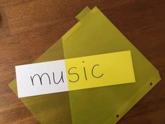 a piece of paper with the word music written on it sitting on top of a wooden table