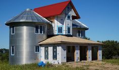 a large metal silo sitting in the middle of a grass field next to a house