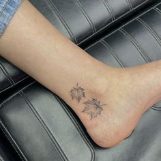 a woman's foot with a tattoo on it that has three leaves attached to it