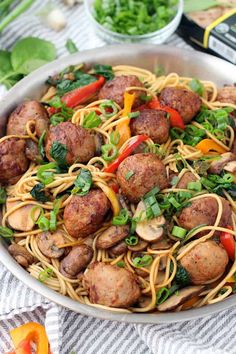 a bowl filled with pasta, meatballs and veggies on top of a table